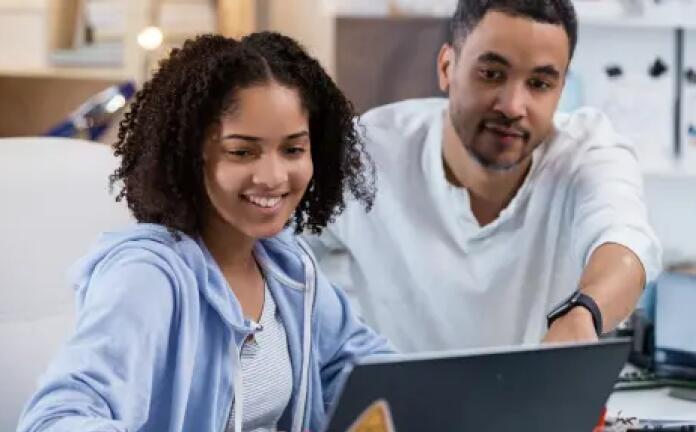 الأب وابنته يعملان معًا باستخدام حاسوبهما المحمول